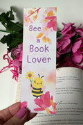 Floral bookmark with bee design held over an open book