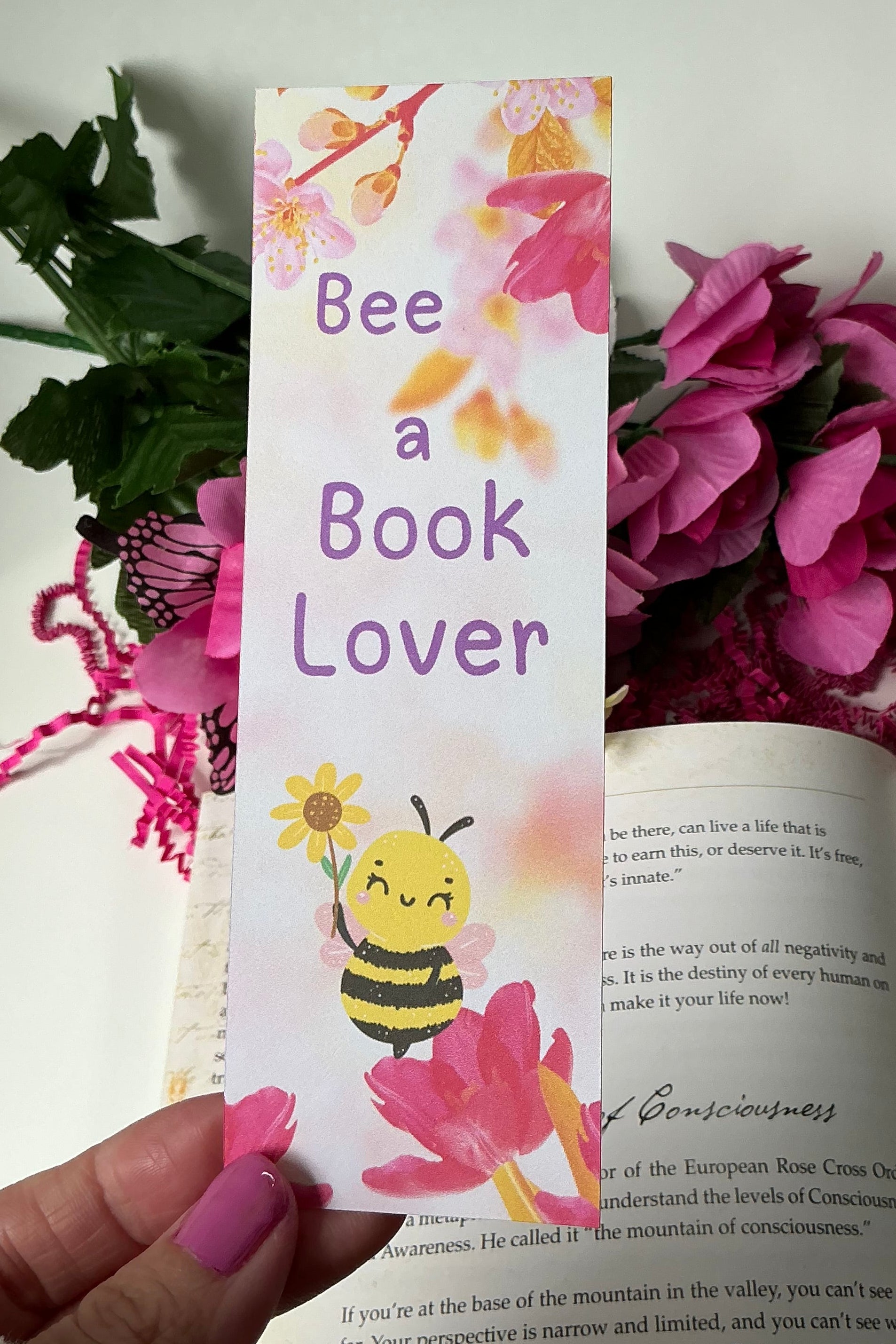 Floral bookmark with bee design held over an open book