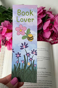 Book Lover bookmark held over an open book with flowers in the background