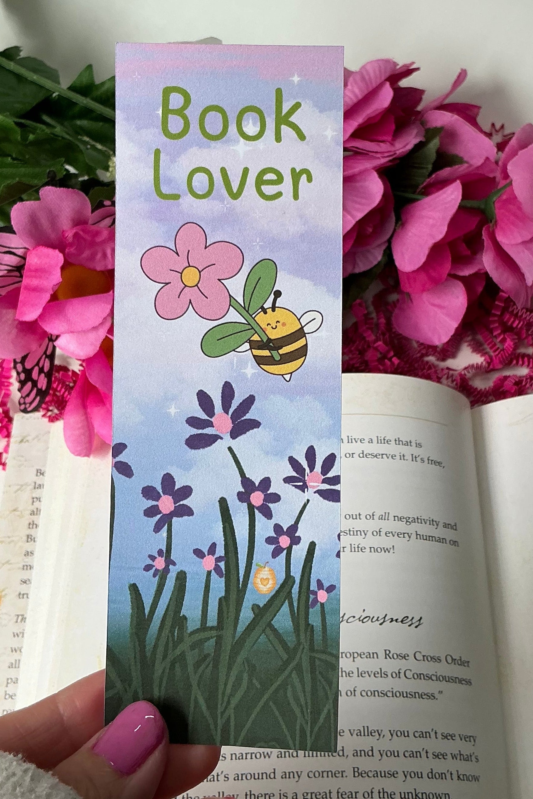 Book Lover bookmark held over an open book with flowers in the background